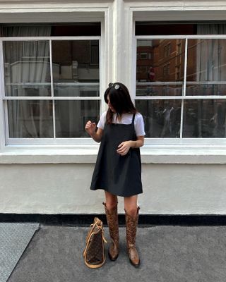 Influencer styles a black mini dress with brown cowboy boots.