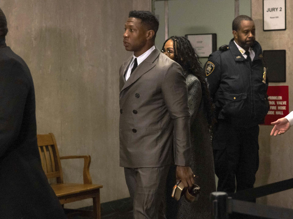 Jonathan Majors, in double-breasted suit and carrying a Bible, a poetry book and a mug, arrives at court with Meagan Good